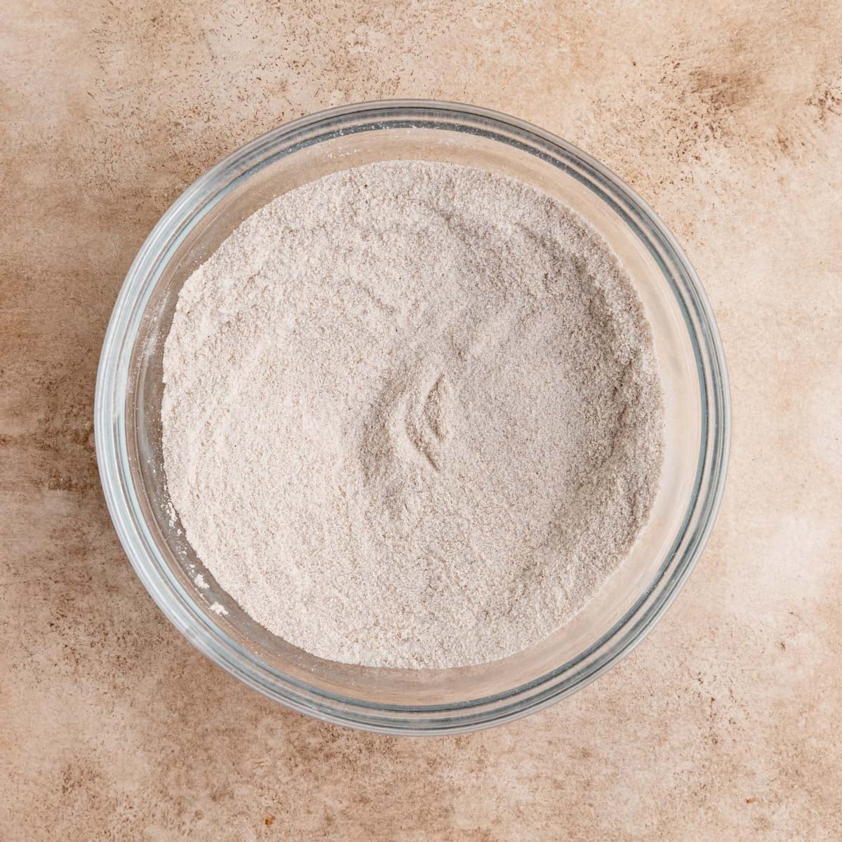 Flour, sugar, cinnamon, nutmeg, cardamon, and salt mixed together in glass bowl