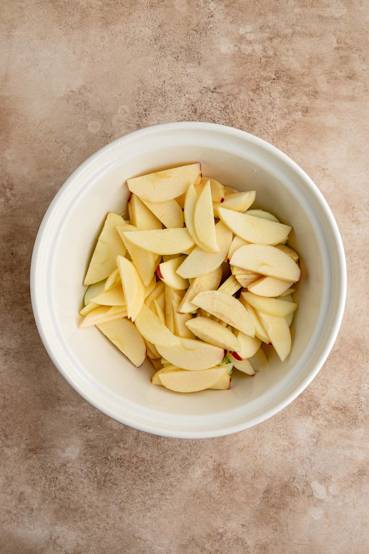 Sliced apples in a large off-white bowl.