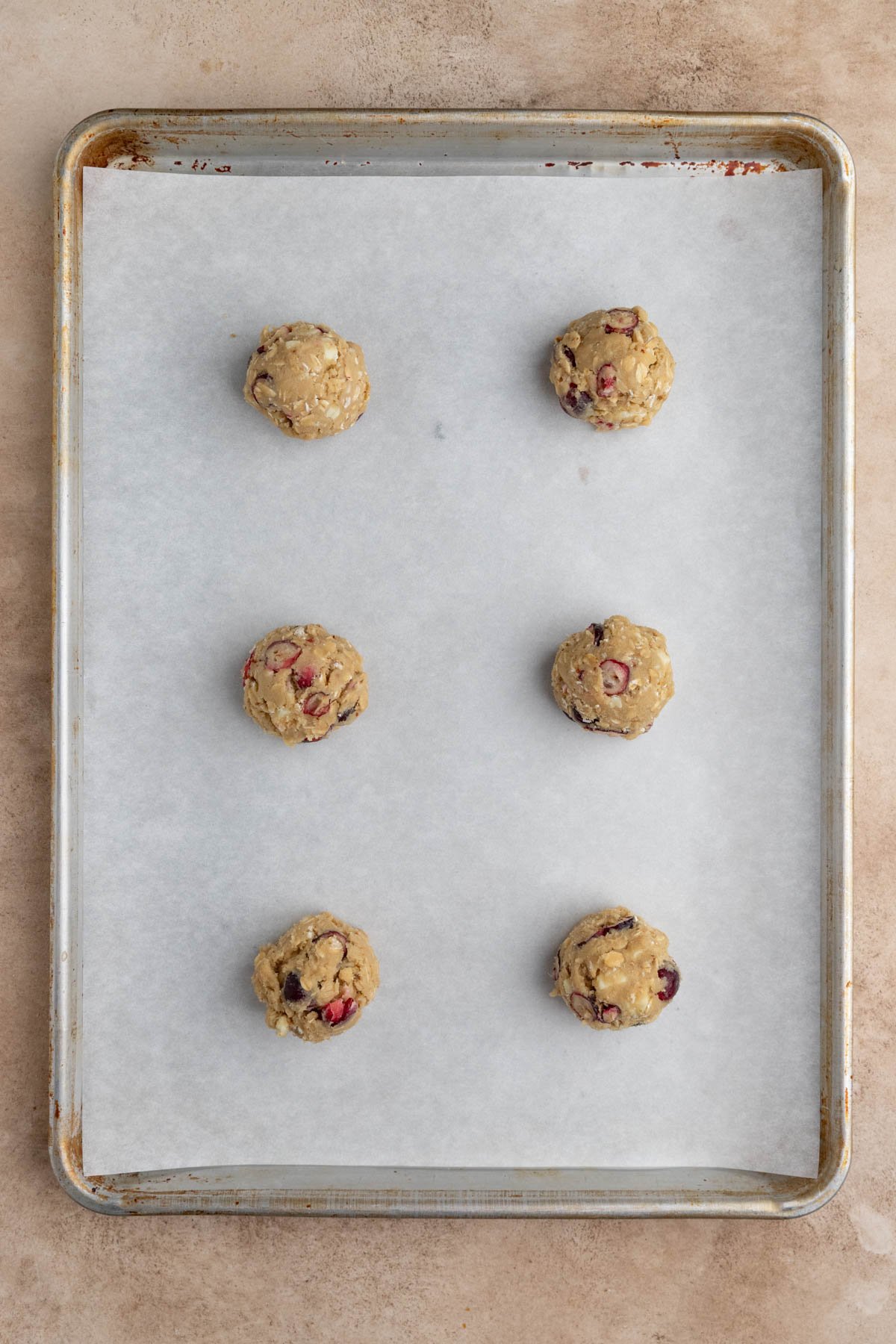 Six balls of dough arranged on a parchment lined half baking sheet