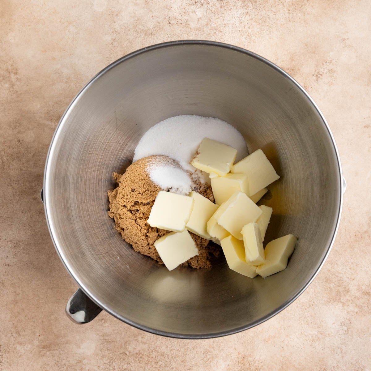 Butter, brown sugar, and granulated sugar in a stainless steel mixing bowl