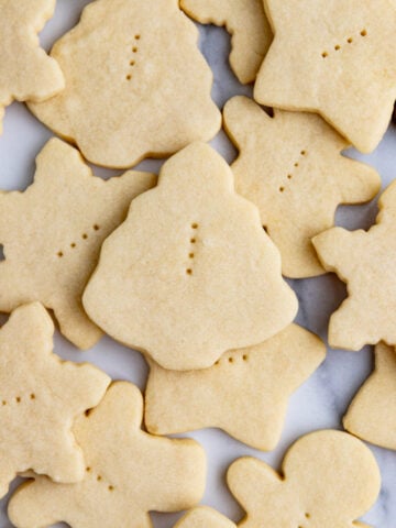 Baked shortbread cookies in various Christmas cookie cutter shapes arranged on a board