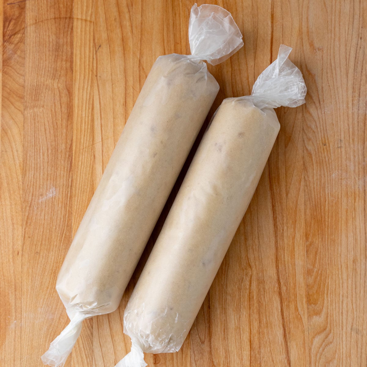 Two dough logs of equal length, each wrapped in wax paper
