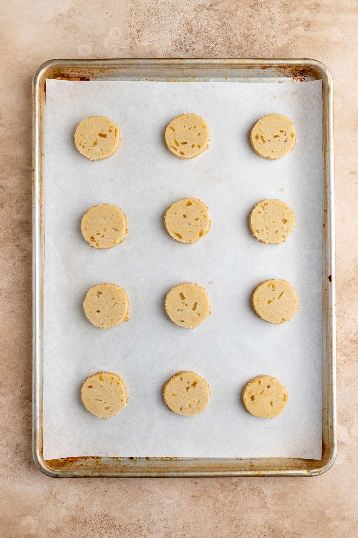 Twelve unbaked cookies arranged on a parchment lined baking sheet