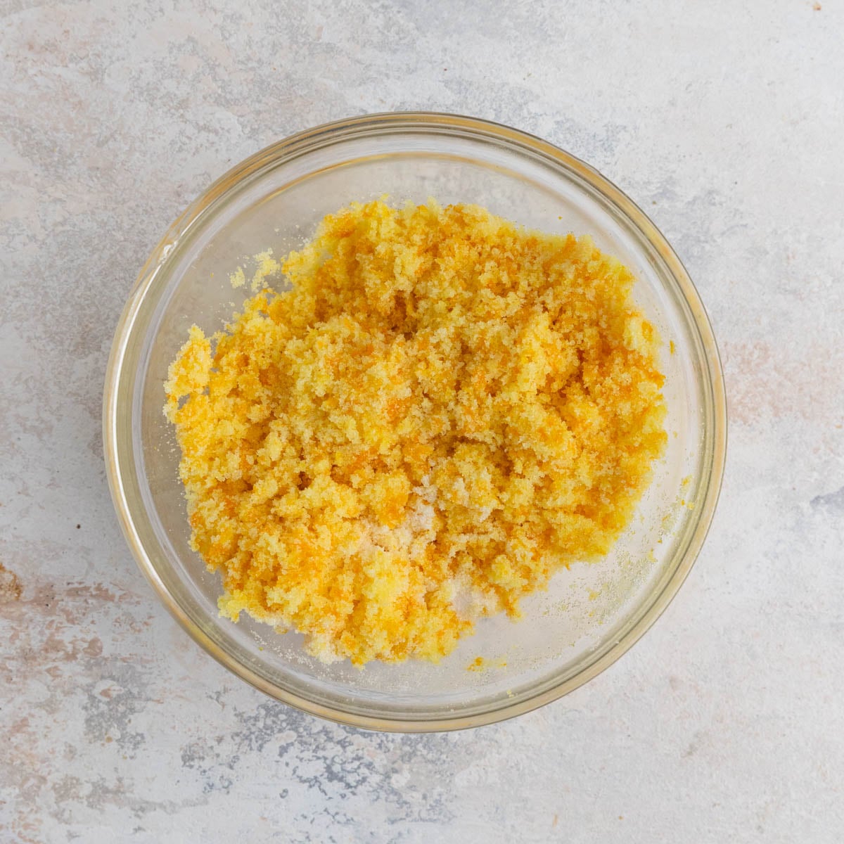 Orange zest rubbed into granulated sugar. The sugar is orange and looks like wet sand