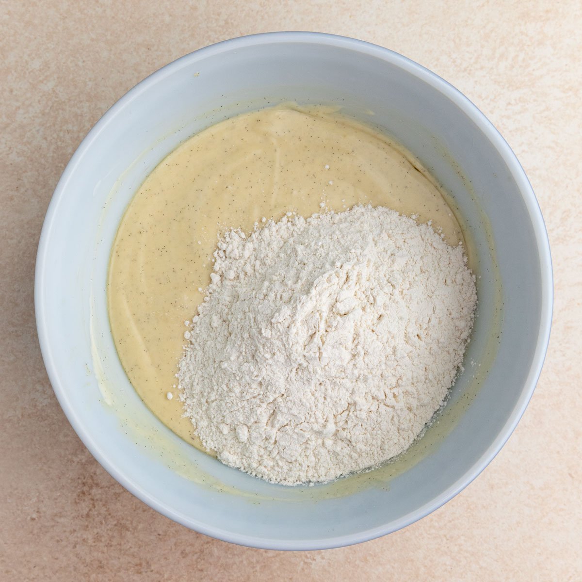 Flour added to the muffin batter in a large mixing bowl