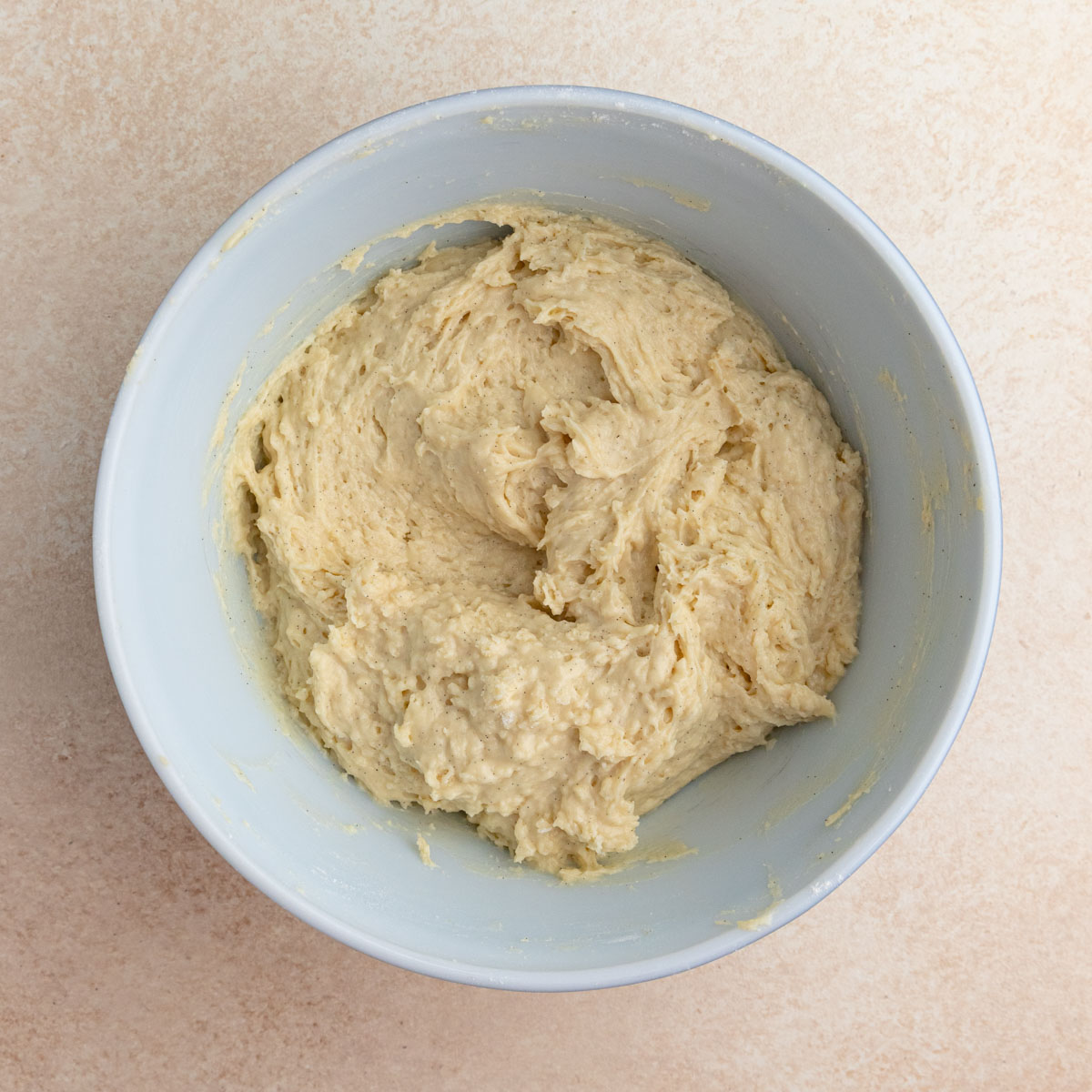 Vanilla muffin batter in a large mixing bowl. It's thick and you can see the flecks of vanilla