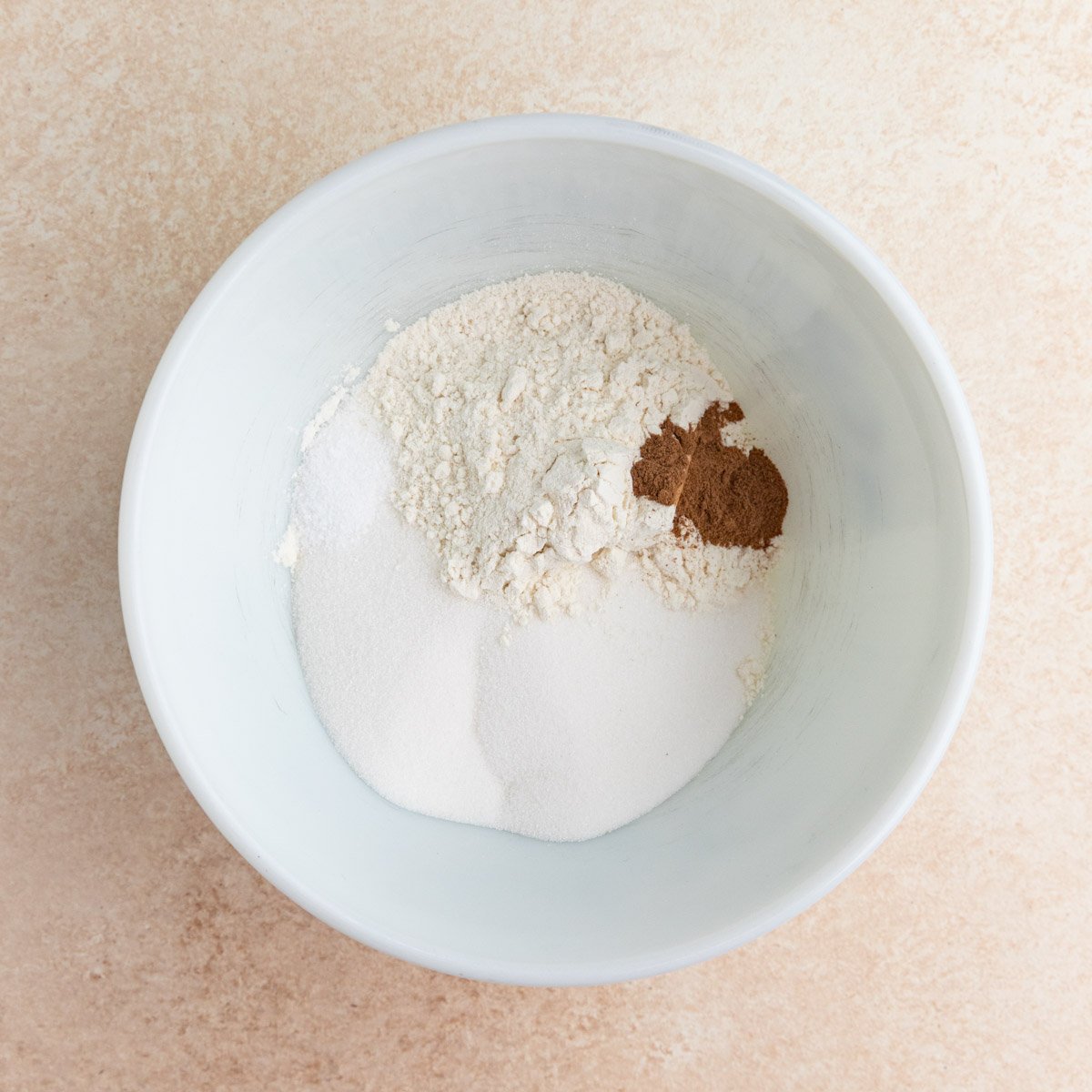 Flour, sugar, salt, and cinnamon in a white ceramic bowl