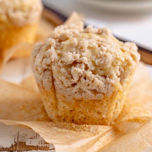 Vanilla muffin with crumble topping on top of a piece of brown parchment paper