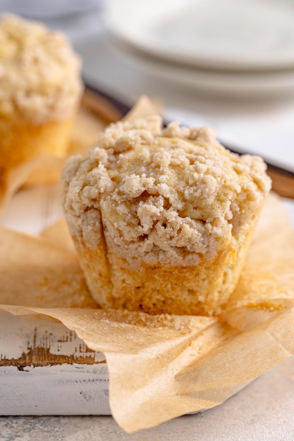 Vanilla muffin with crumble topping on top of a piece of brown parchment paper