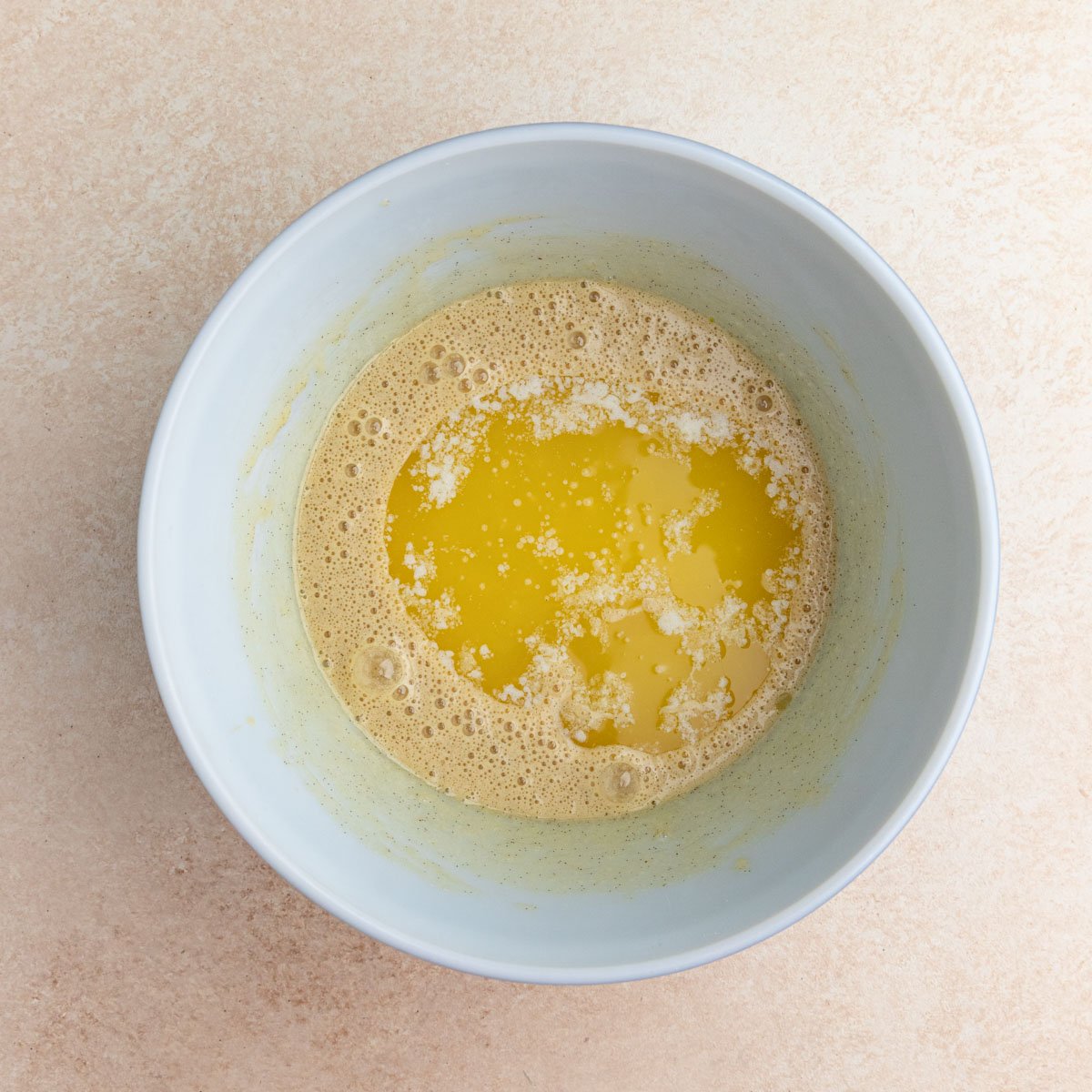 Melted butter added to the muffin batter in a large bowl