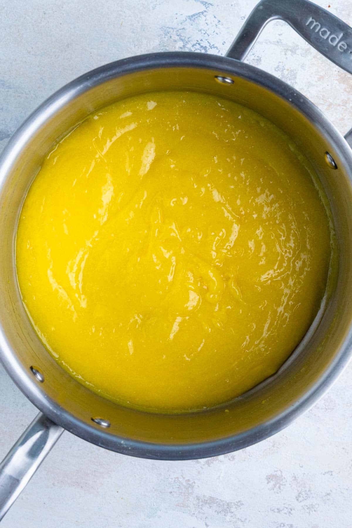Bright yellow lemon curd in a large sauce pan