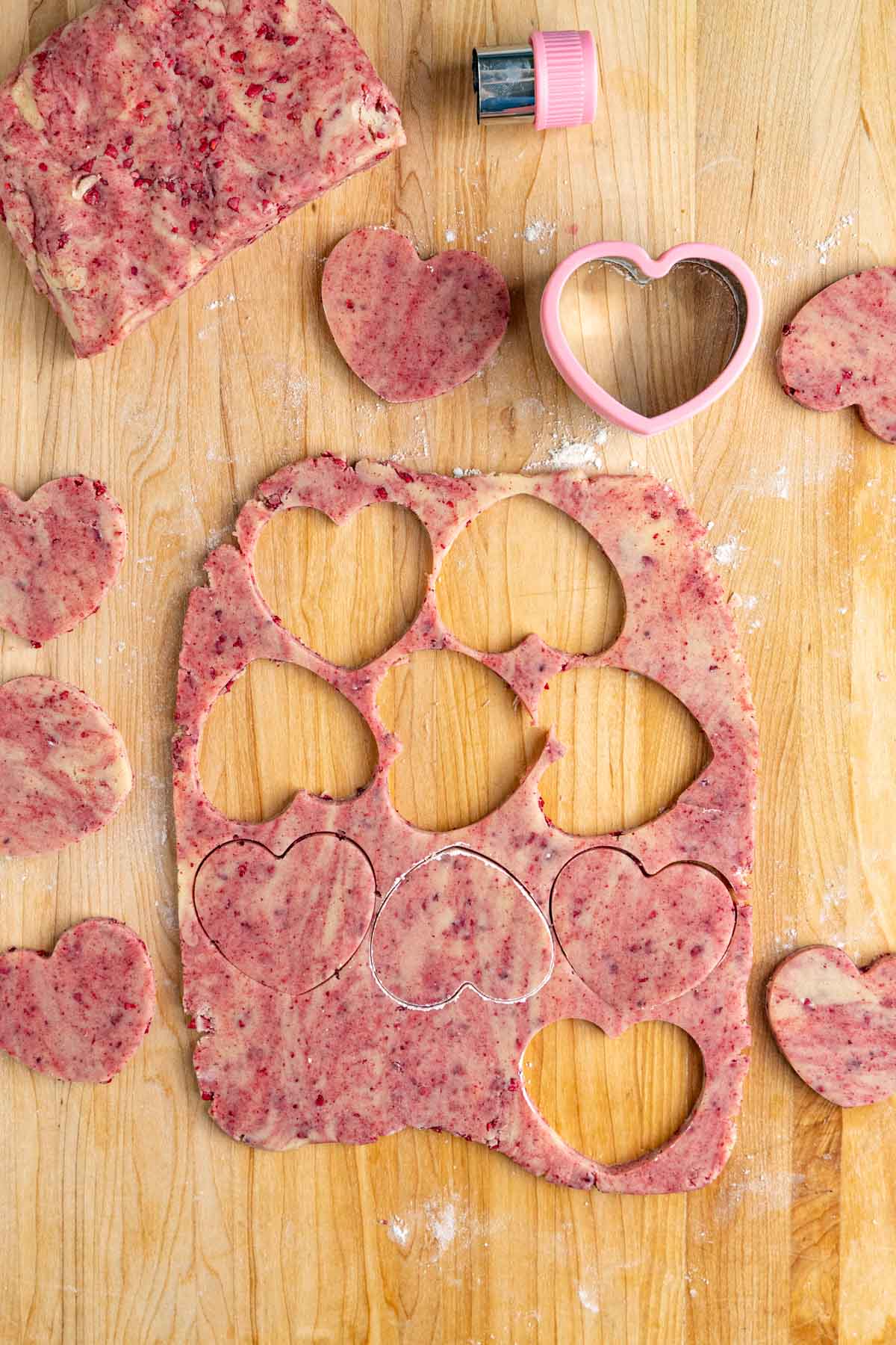 Raspberry shortbread cookie dough rolled out and cut out with heart-shaped cookie dough