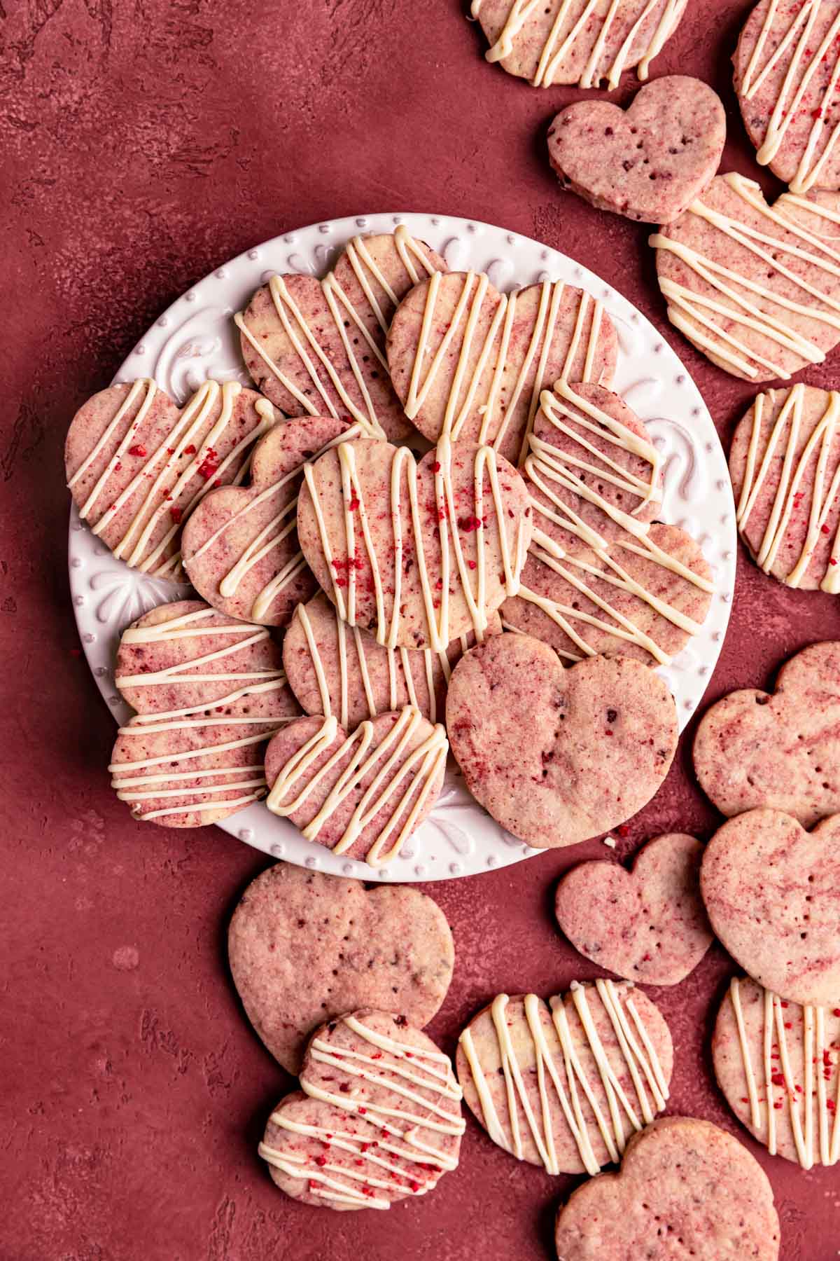 Raspberry shortbread cookies with a white chocolate drizzle arranged on a white ceramic plate