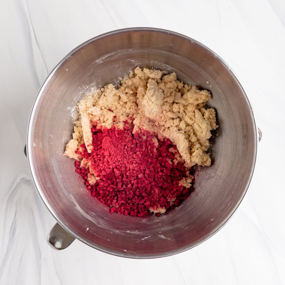Freeze-dried raspberries added to the shortbread cookie dough in the bowl of a stand mixer