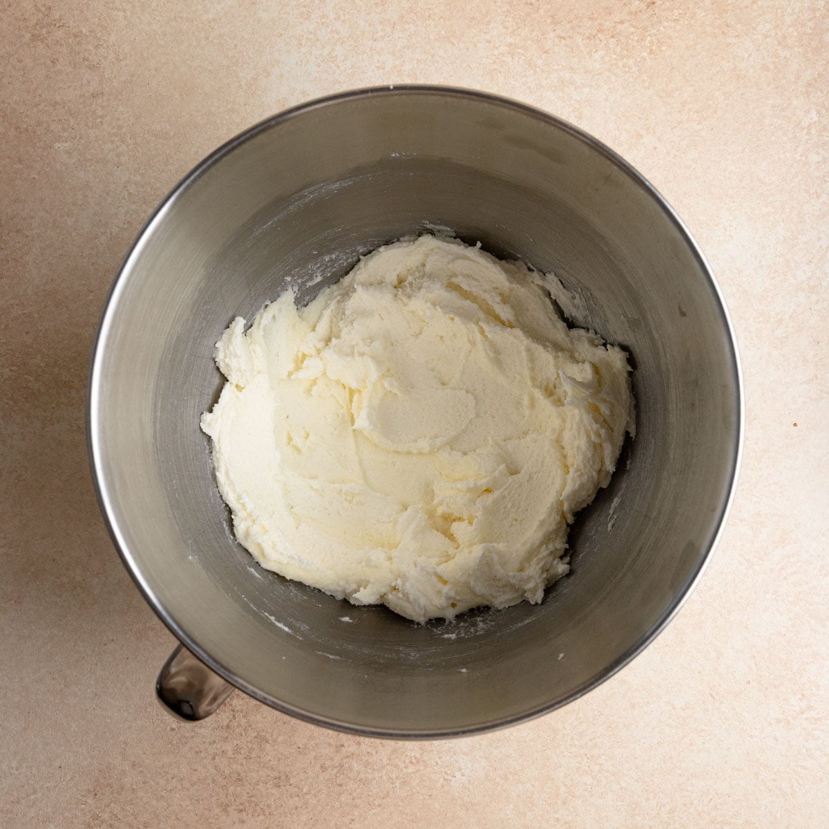 Creamed butter and sugar in the bowl of a stand mixer. The color is a very light yellow.
