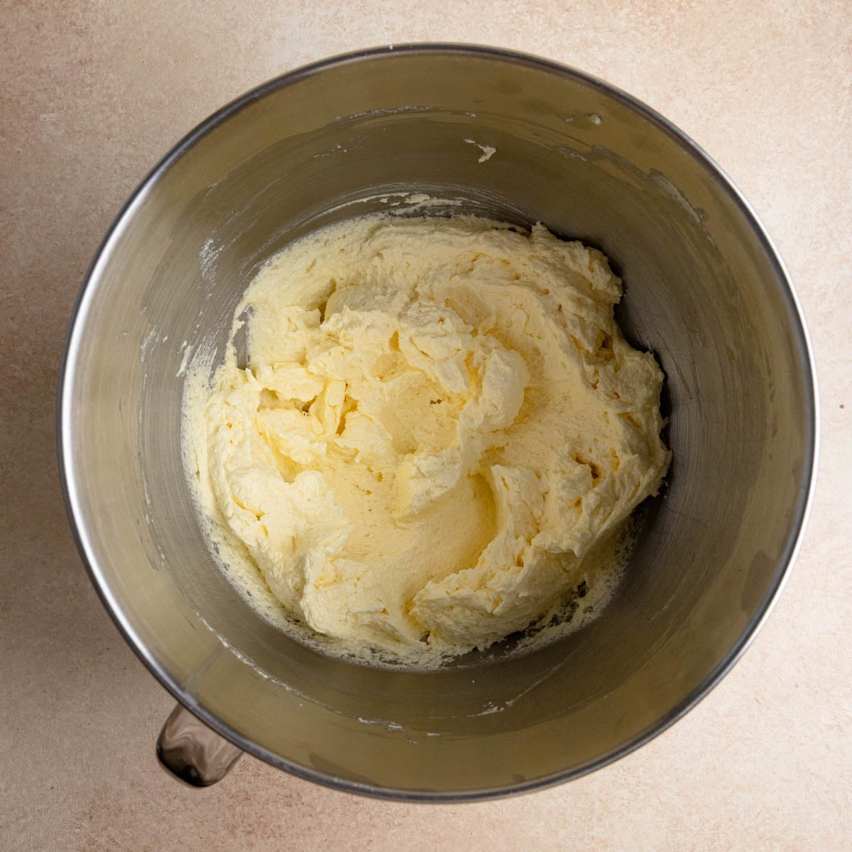 Cake batter in the bowl of a stand mixer. The batter is creamy and light yellow