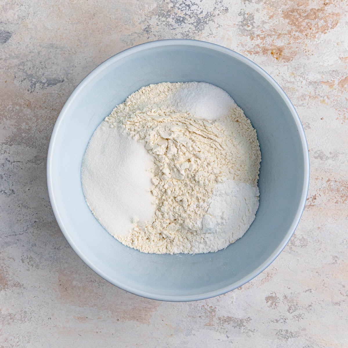 Flour, baking powder, sugar, and kosher salt in a white ceramic bowl