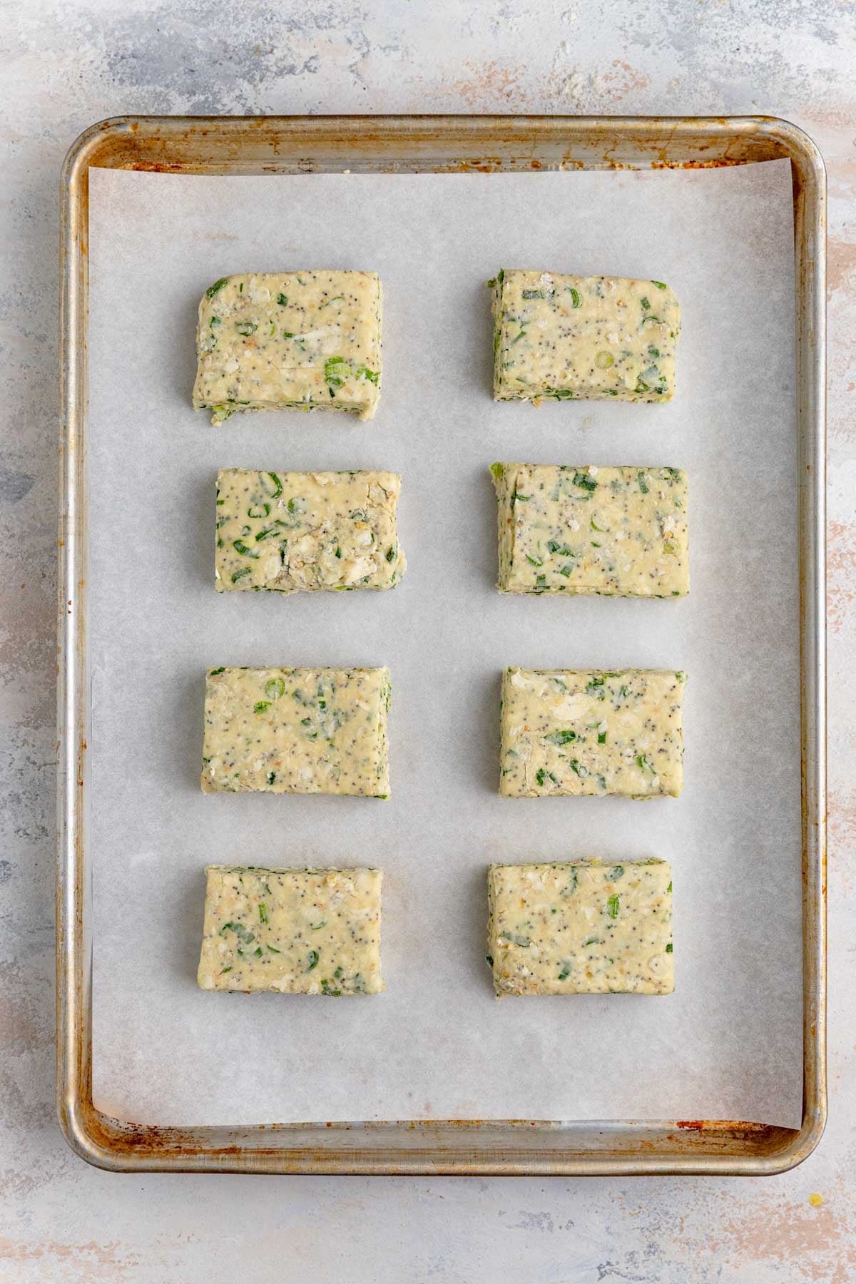 Eight unbaked scones arranged on two rows on a parchment-lined baking sheet