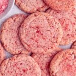Several sugar cookies laid on a surface. The cookies are round, pink, with a strawberry sugar coating