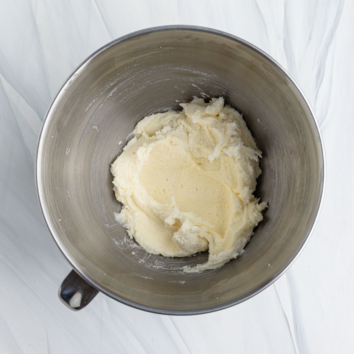 Creamed butter and sugar in the stainless steel bowl of a stand mixer