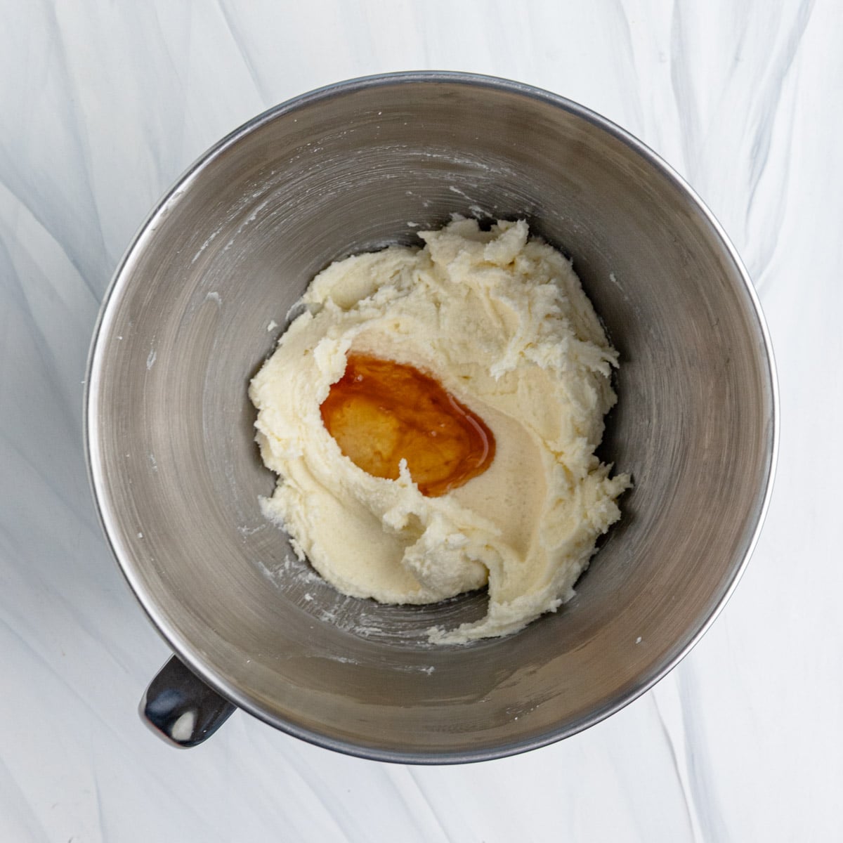 Egg whites and vanilla extract added to the creamed sugar and butter in the stainless steel bowl of stand mixer