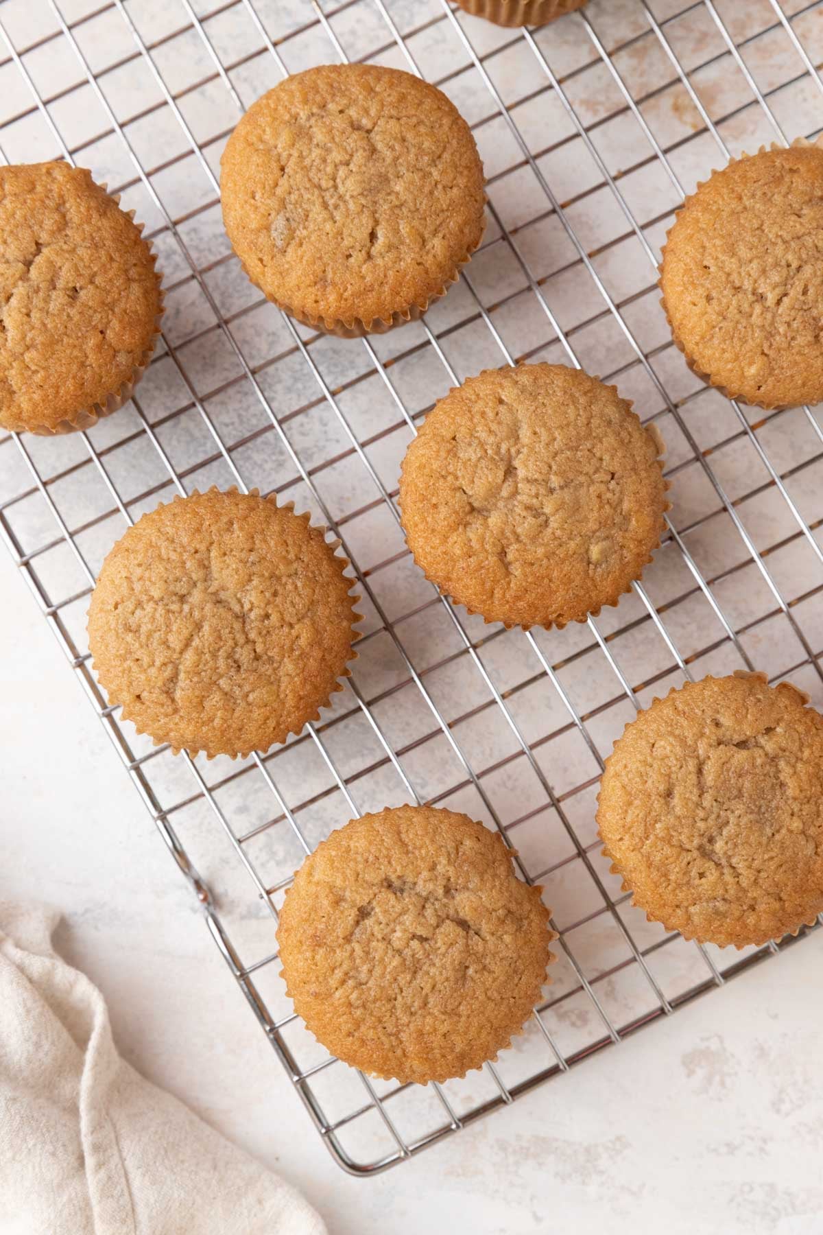 Seven baked banana cupcakes on a wire cooling rack