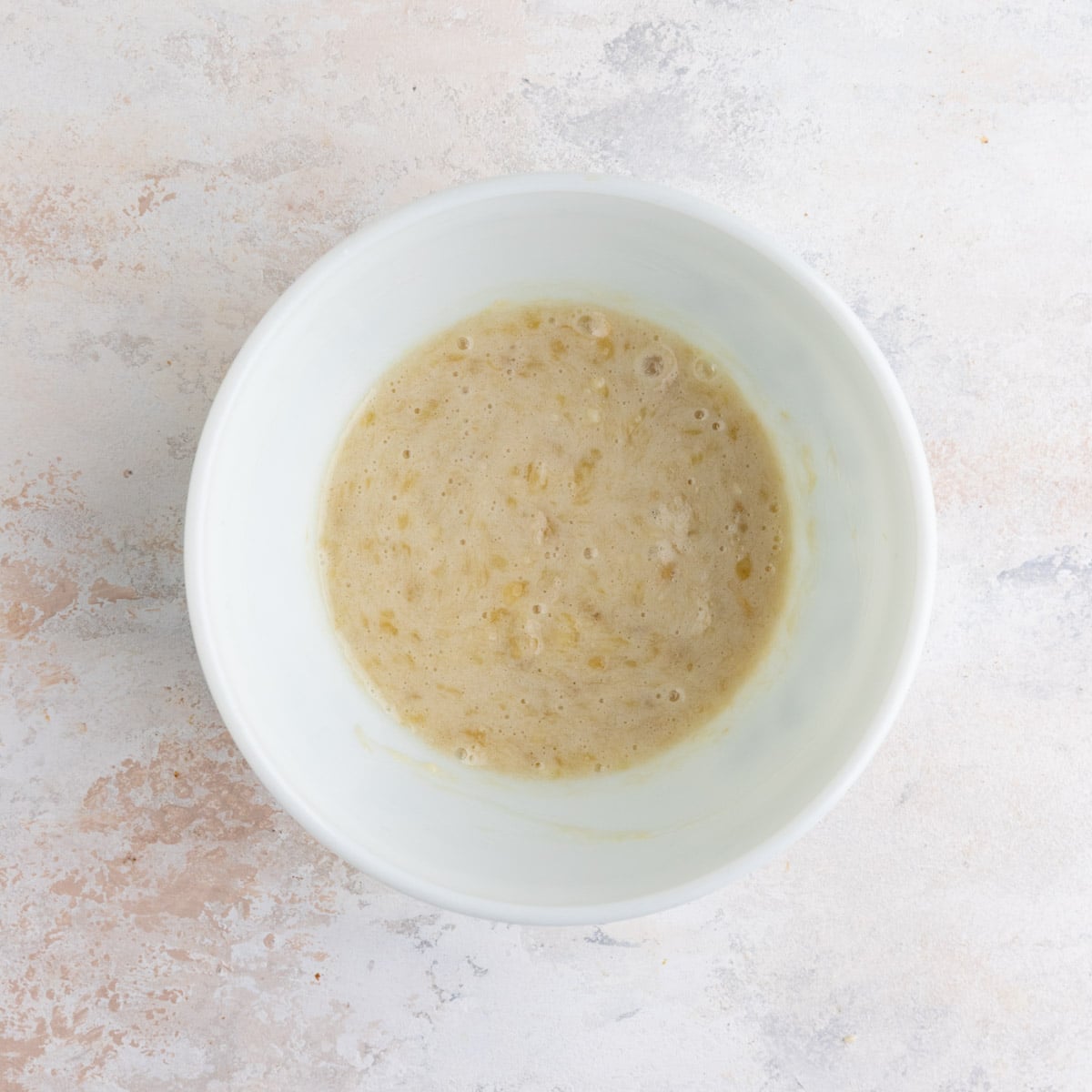 Pureed bananas in a white ceramic bowl.