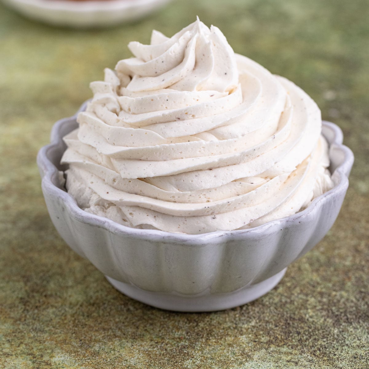 Piped vanilla ermine frosting in a white ceramic bowl