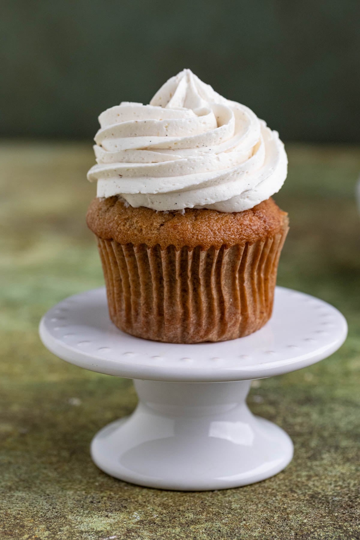 Vanilla ermine frosting piped on top of a cupcake.  The cupcake is on a mini cake stand