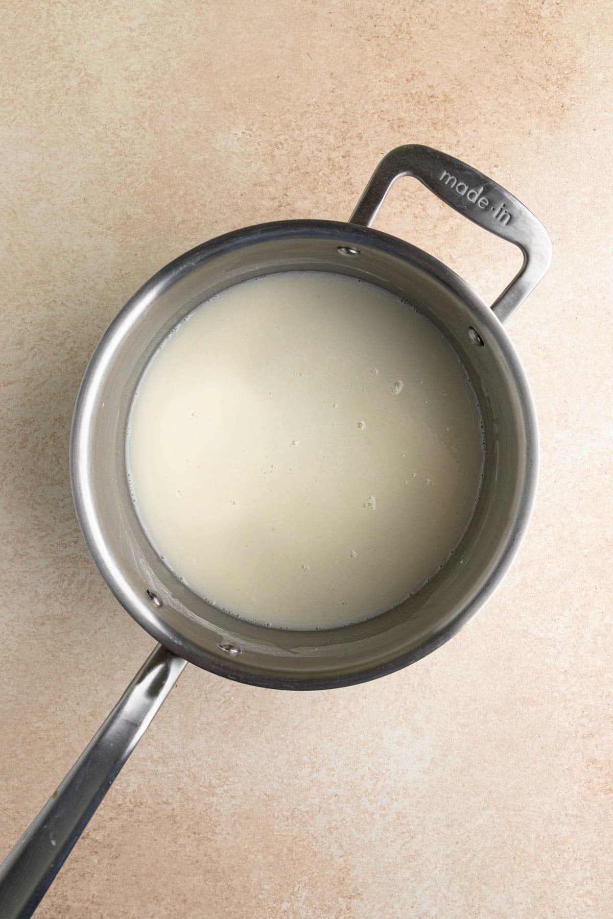 Sugar, flour, cornstarch, salt and milk whisked together in a stainless steel saucepan.  The mixture is an off-white color.