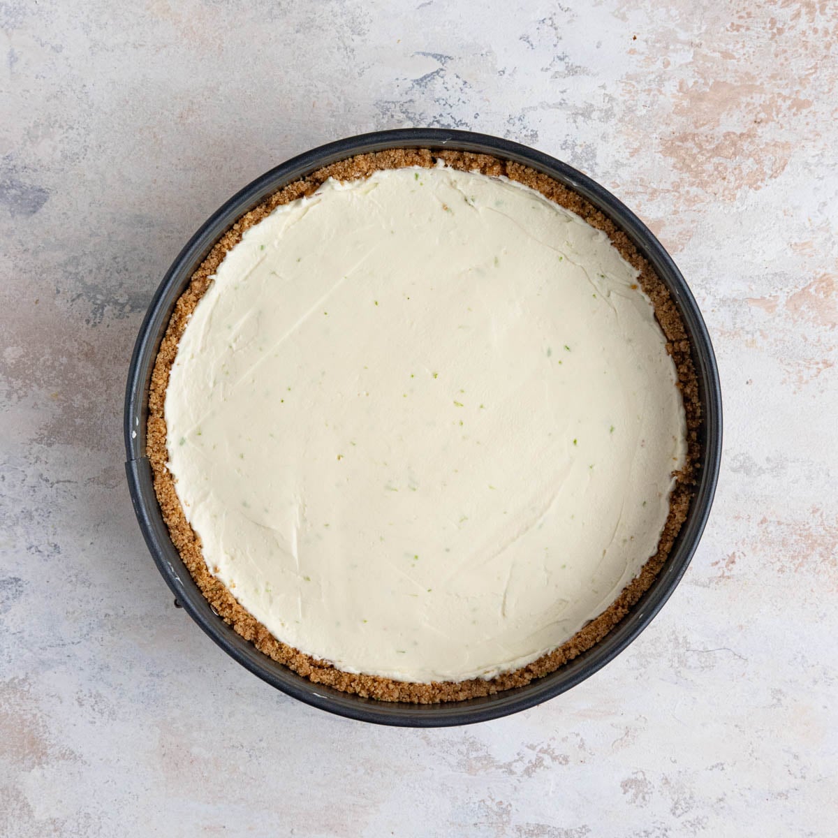 The key lime cheesecake filling in a graham cracker crust in a springform pan