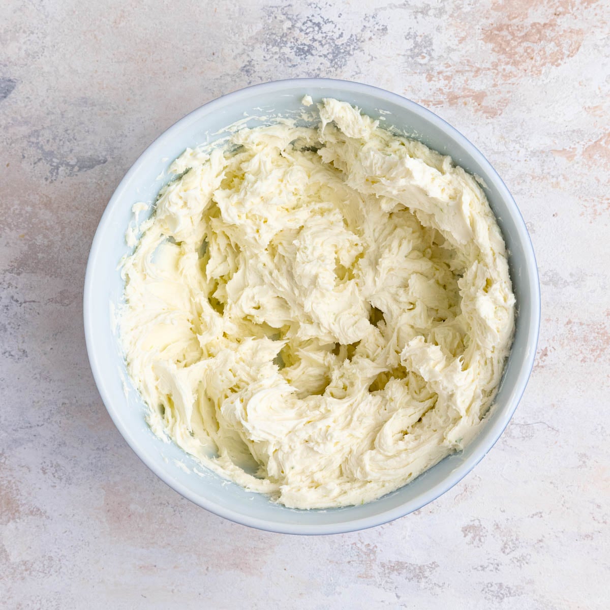 Cream cheese, mascarpone, sugar, and lime zest whipped together in a ceramic mixing bowl