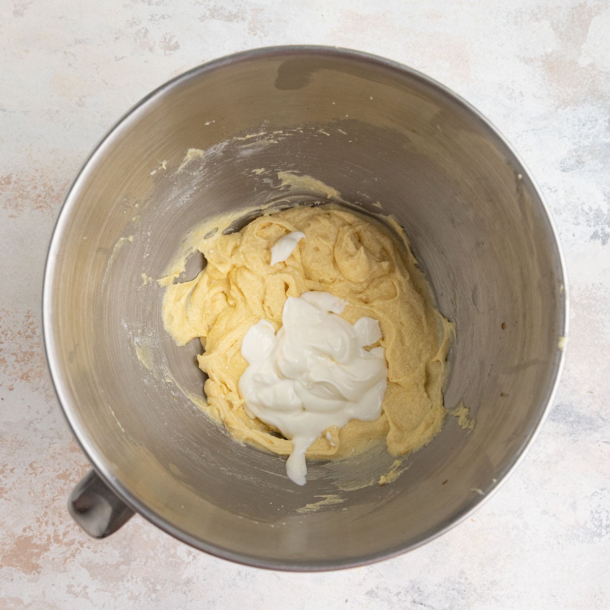 Half of the sour cream added to the batter in a stainless steel mixing bowl