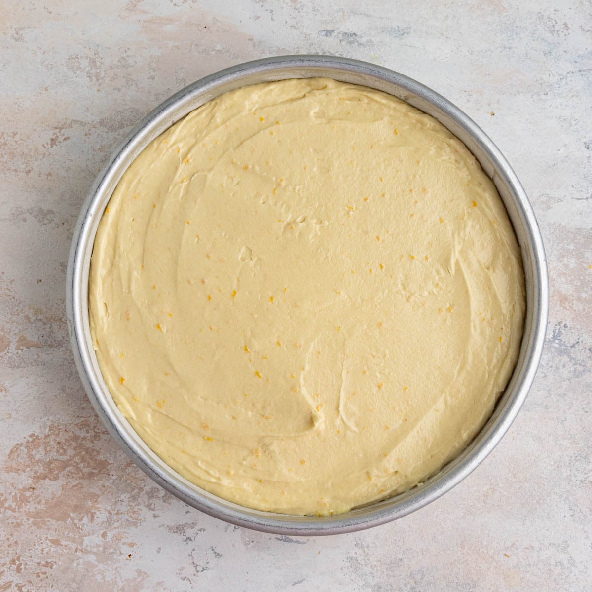 A round cake pan with the upside down cake batter smoothed across the top.