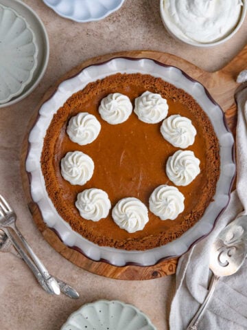 Baked sweet potato pie decorated with swirls of whipped cream.