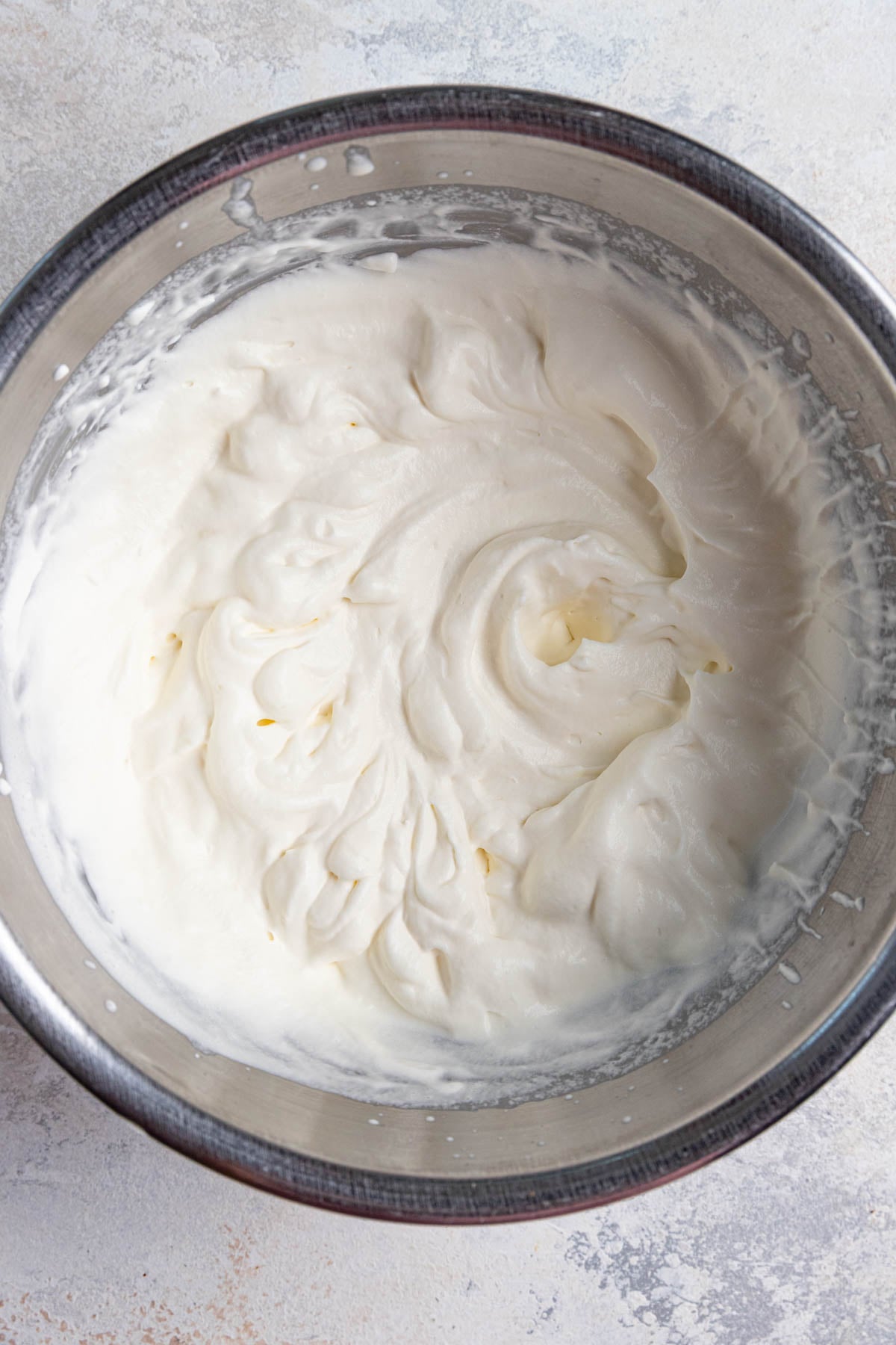 Whipped cream with soft peaks in a stainless steel bowl