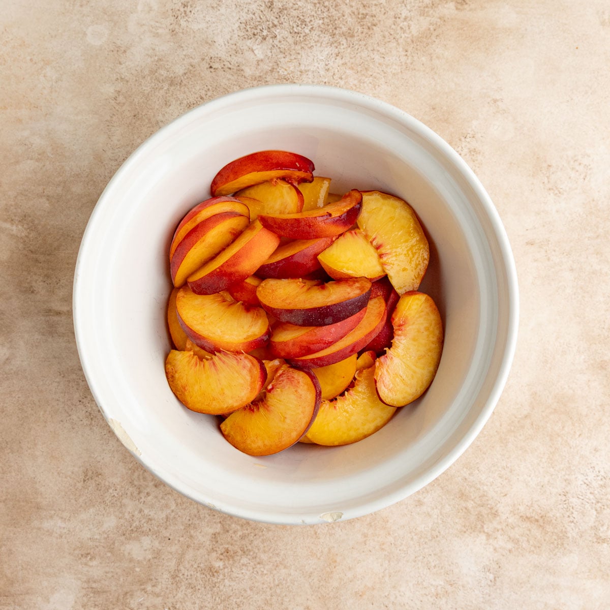 Sliced peaches in a white ceramic bowl
