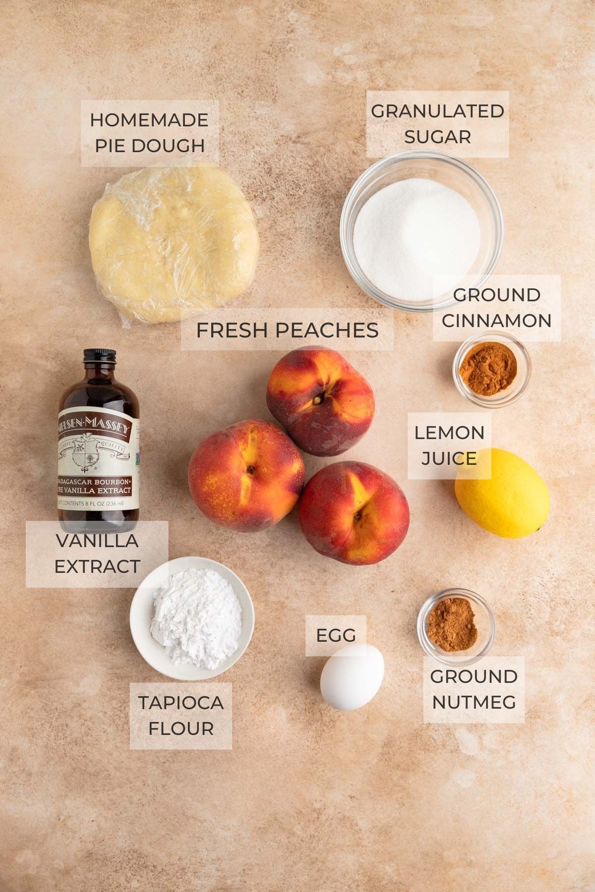 Peach galette ingredients: pie dough, granulated sugar, ground cinnamon, a lemon, ground nutmeg, tapioca flour, fresh peaches, vanilla extract