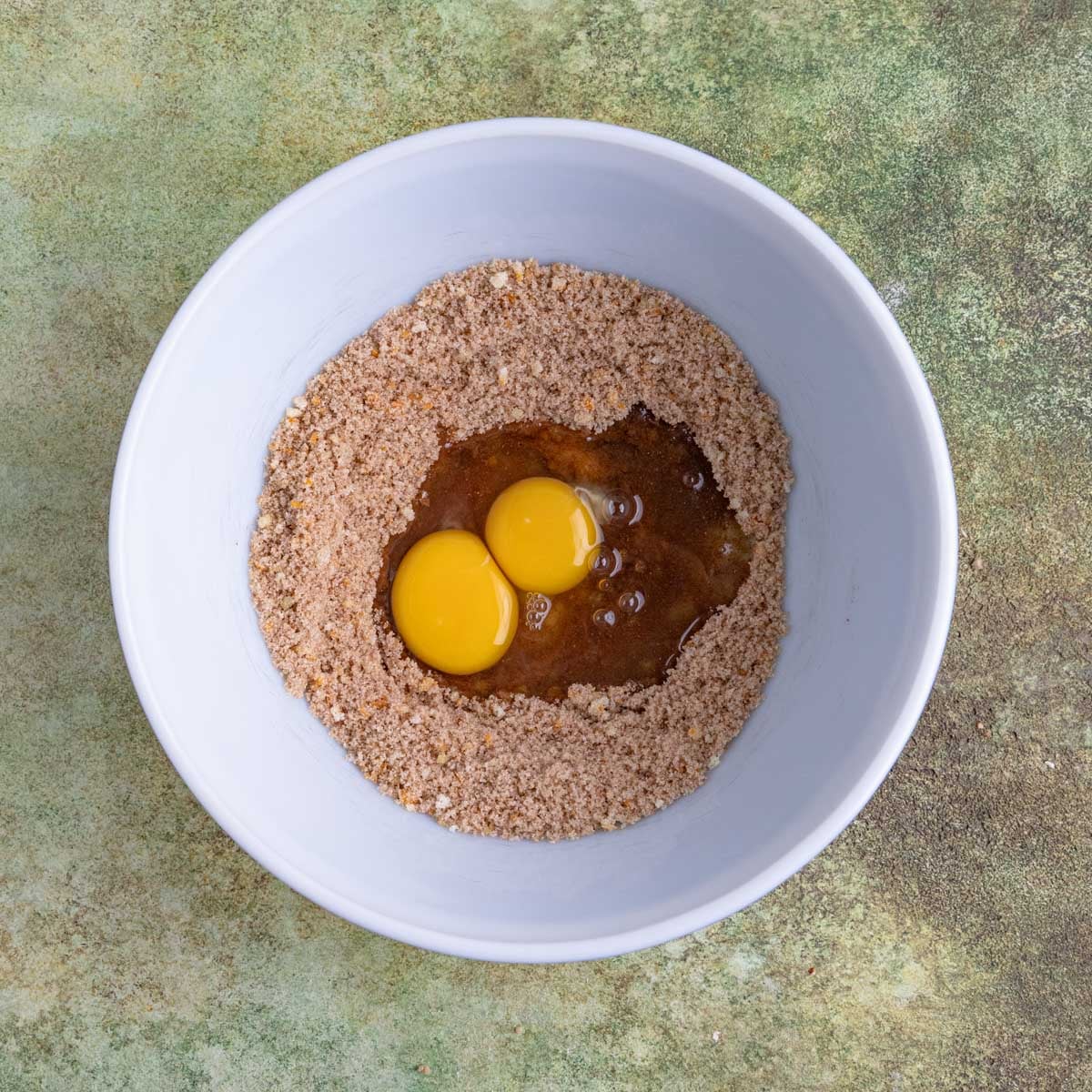 Two eggs added to the sugar and spice mixture in a large ceramic bowl