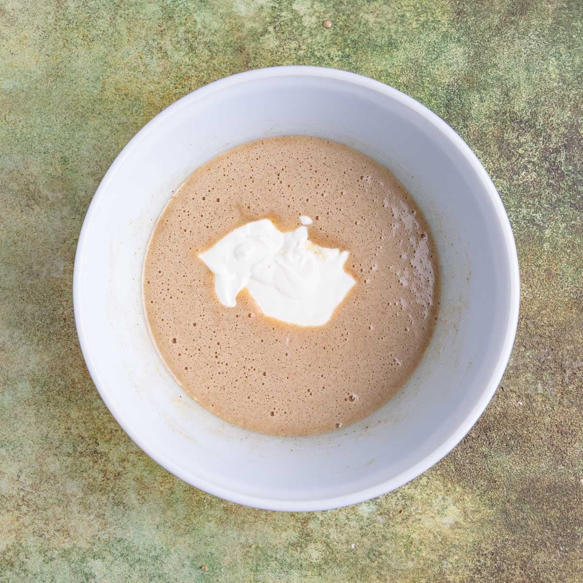 Muffin batter in a ceramic bowl with sour cream added