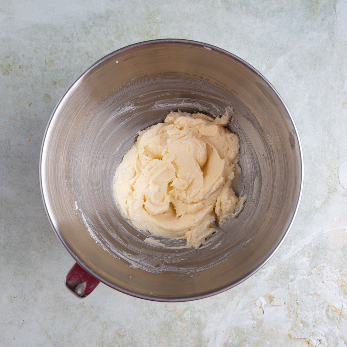Butter, sugar, lemon zest, and vanilla beaten together in a the bowl of a stand mixer. The mixer is light yellow and creamy.