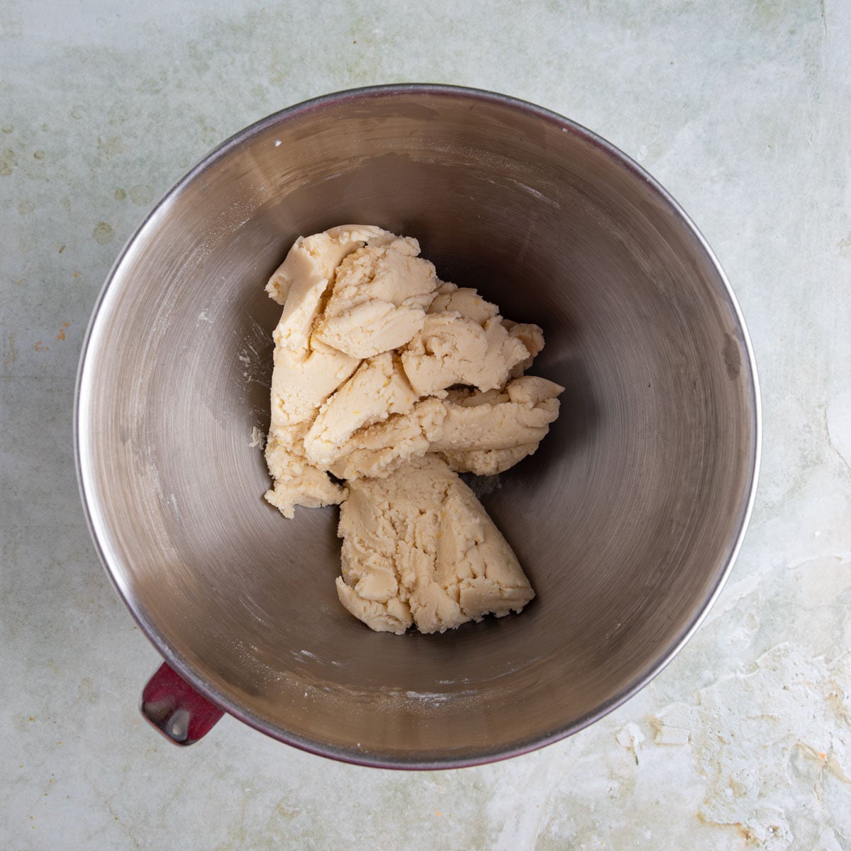 Shortbread cookie dough in the bowl of a stainless steel mixer. The dough is off-white.