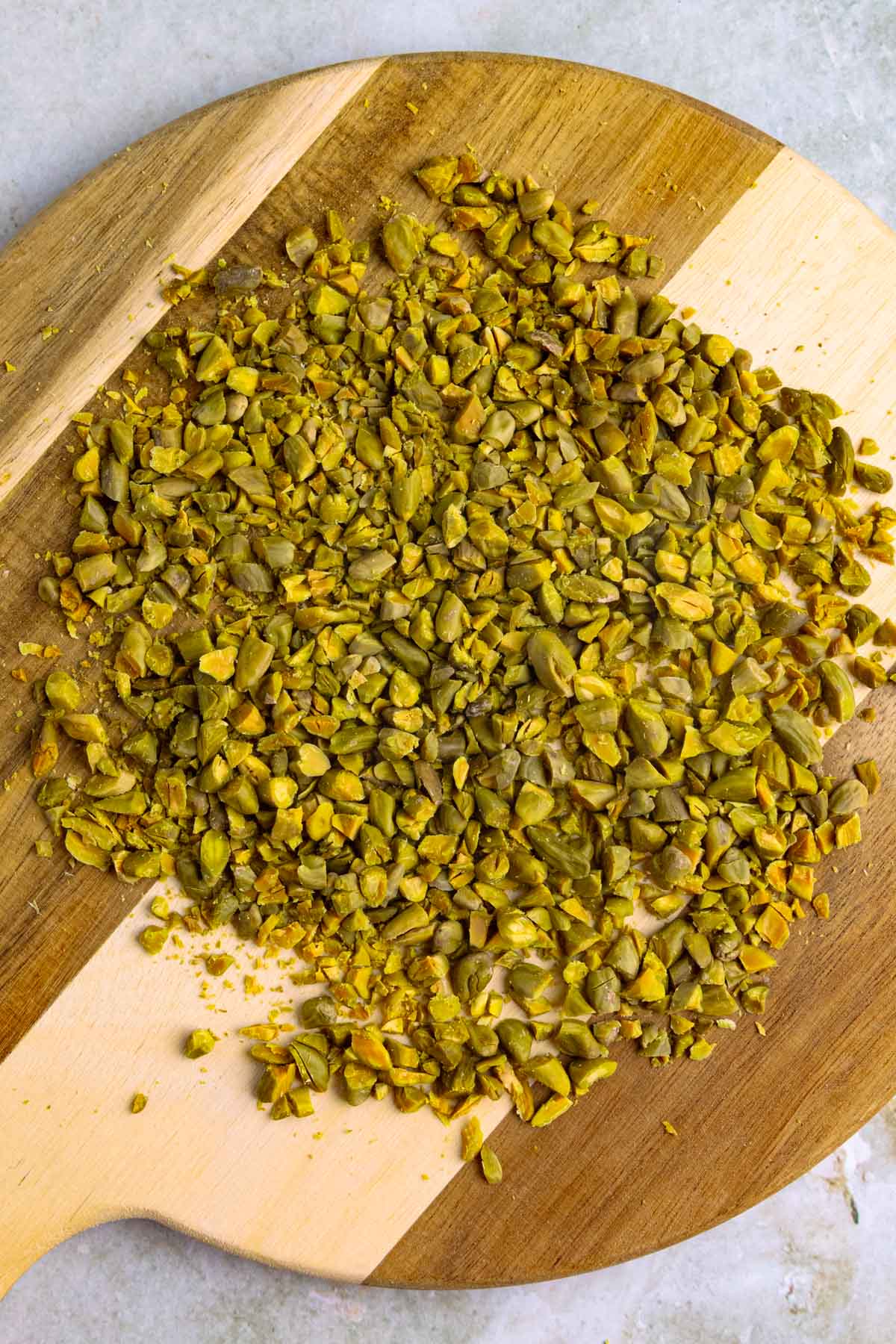 Chopped green pistachios on a wooden cutting board