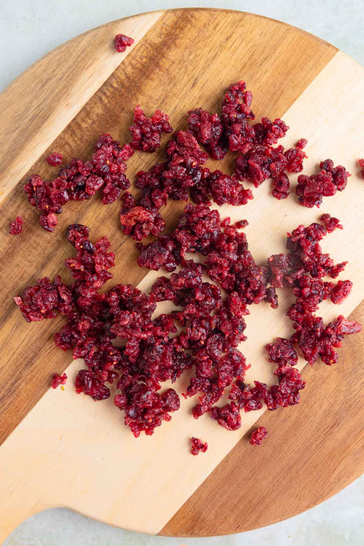 Chopped dried sweetened cranberries on a wooden cutting board